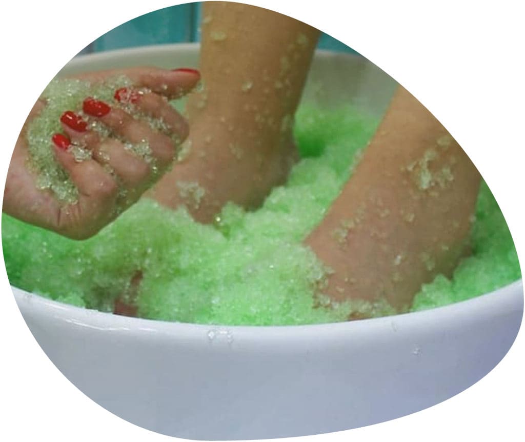 Momento del tratamiento de la pedicura Jelly spa, unos pies están dentro de una bañera con burbujas verdes con el tratamiento de la pedicura